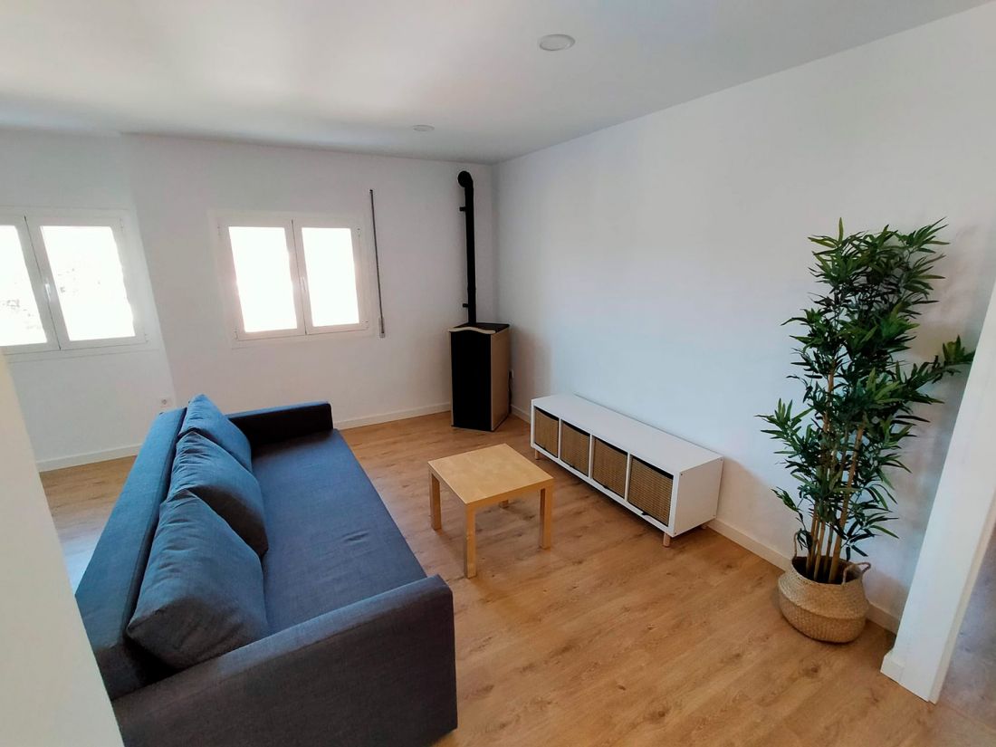 Salón de vivienda reformado con tarima de madera en color claro y muebles modernos